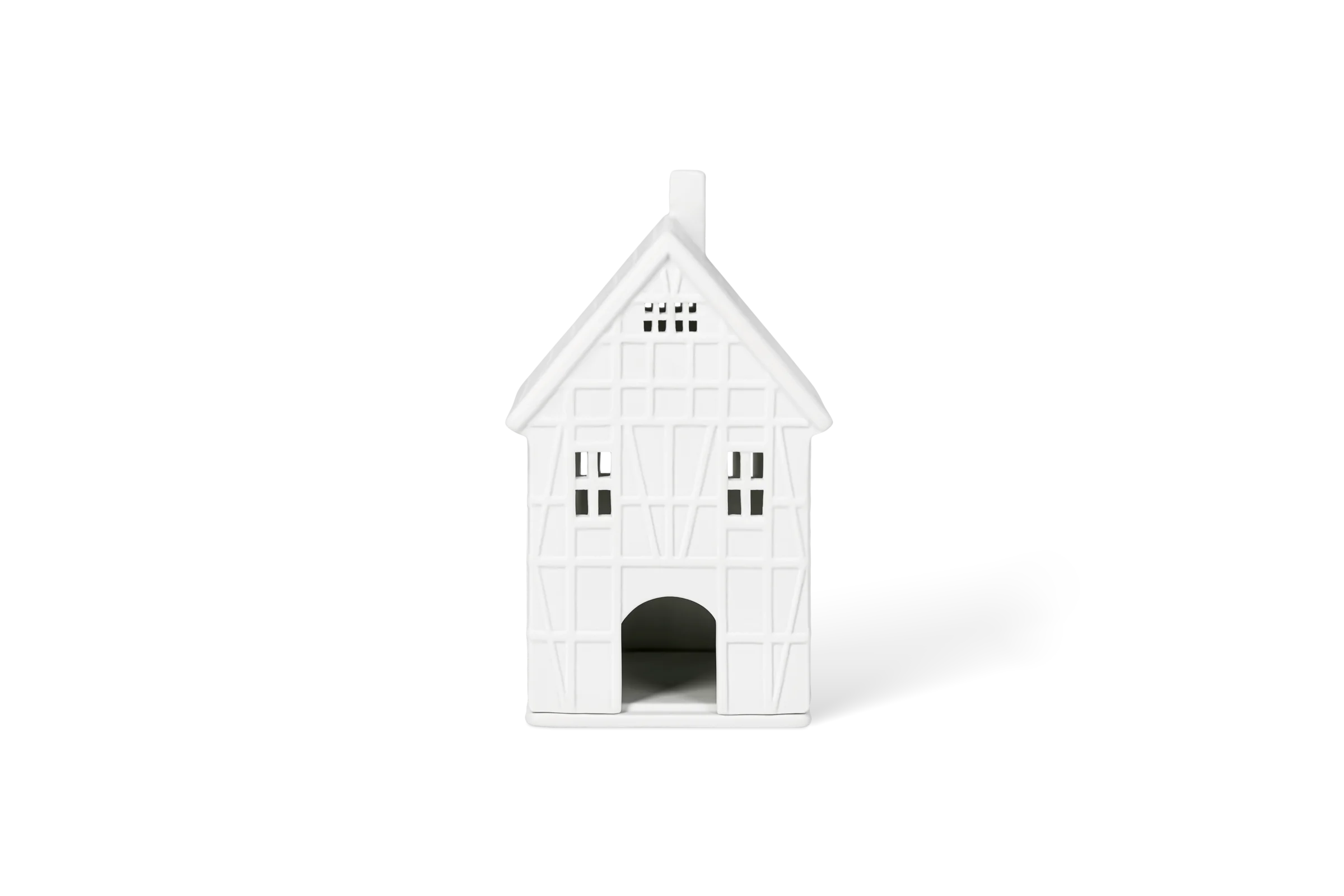 Weißes Lichthaus in Fachwerkoptik mit Fenstern, Torbogen und tiefgeprägten Wanddetails in der Vorderansicht.