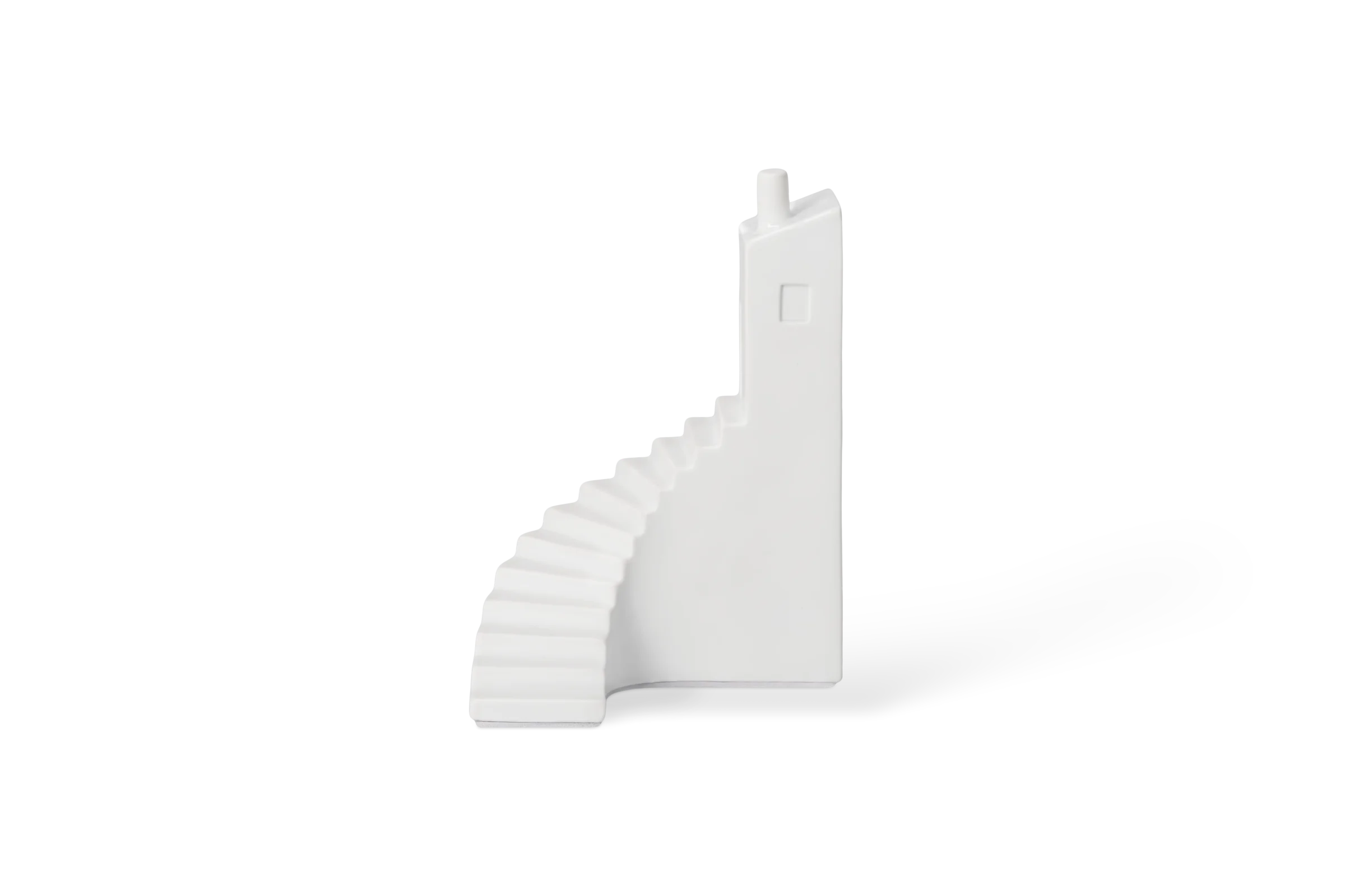 Weiße Buchstütze Büchertreppchen in Form einer geschwungenen Treppe mit Hausfassade, Fenster und Schornstein in der Rechtsansicht.