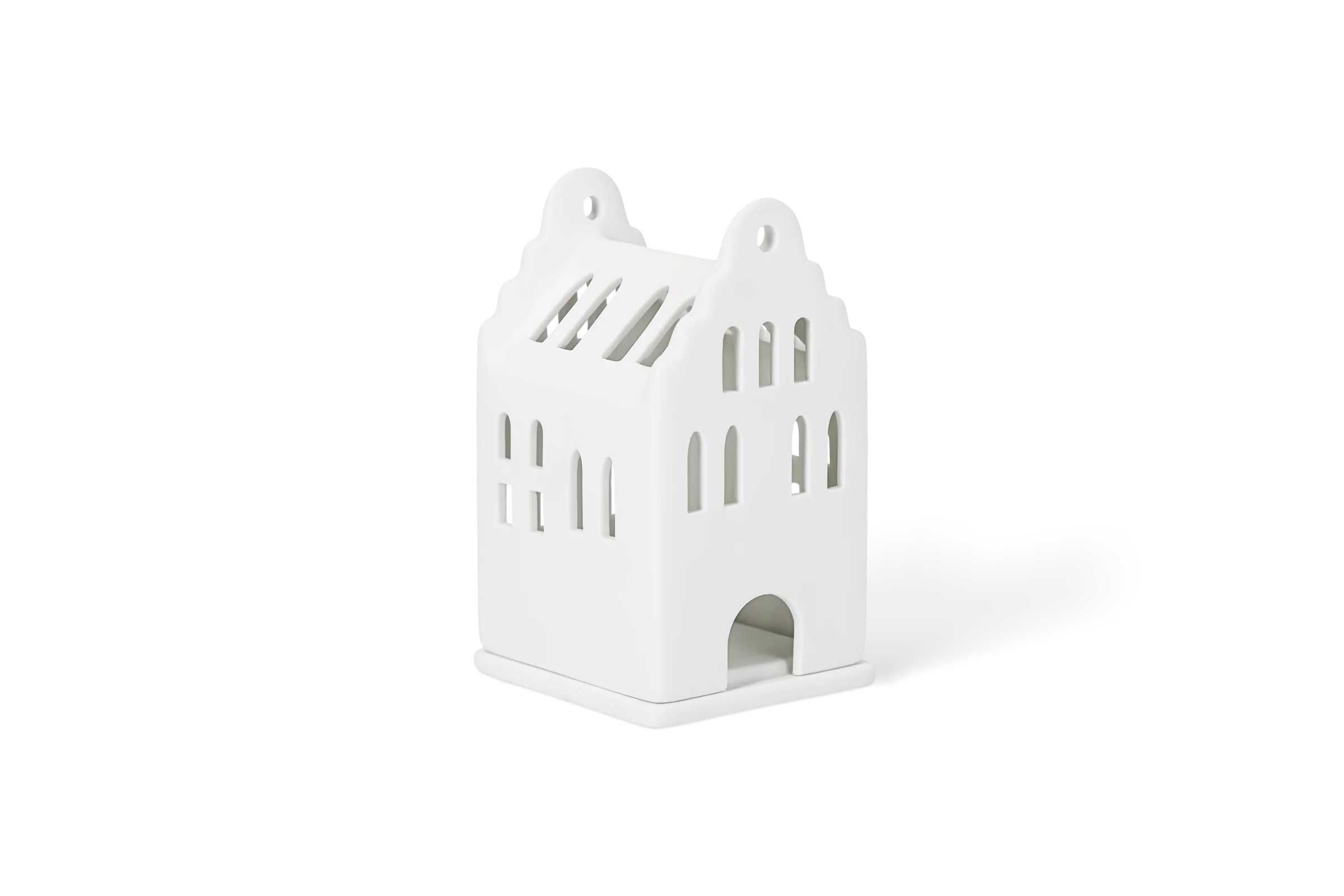 Mini-Lichthaus Giebelhaus Weißes Lichthaus aus Porzellan mit Spitzdächern, Fensteröffnungen und Torbogen in der vorderen Linksansicht.