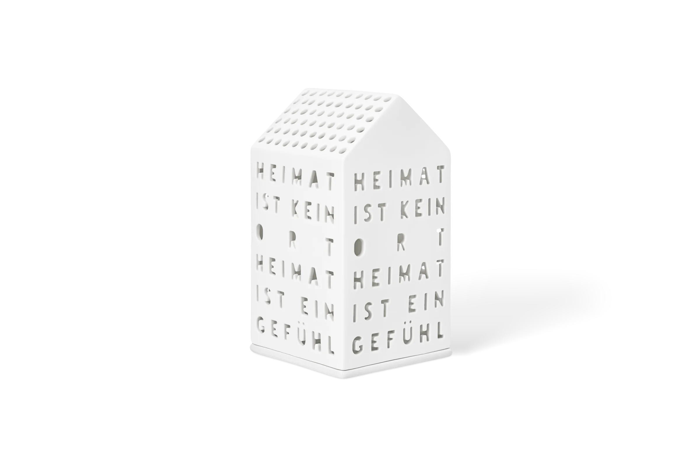 Lichthaus Heimat ist kein Ort Weißes Porzellanlichthaus mit durchbrochenem Schriftzug Heimat ist kein Ort Heimat ist ein Gefühl in der vorderen Linksansicht.
