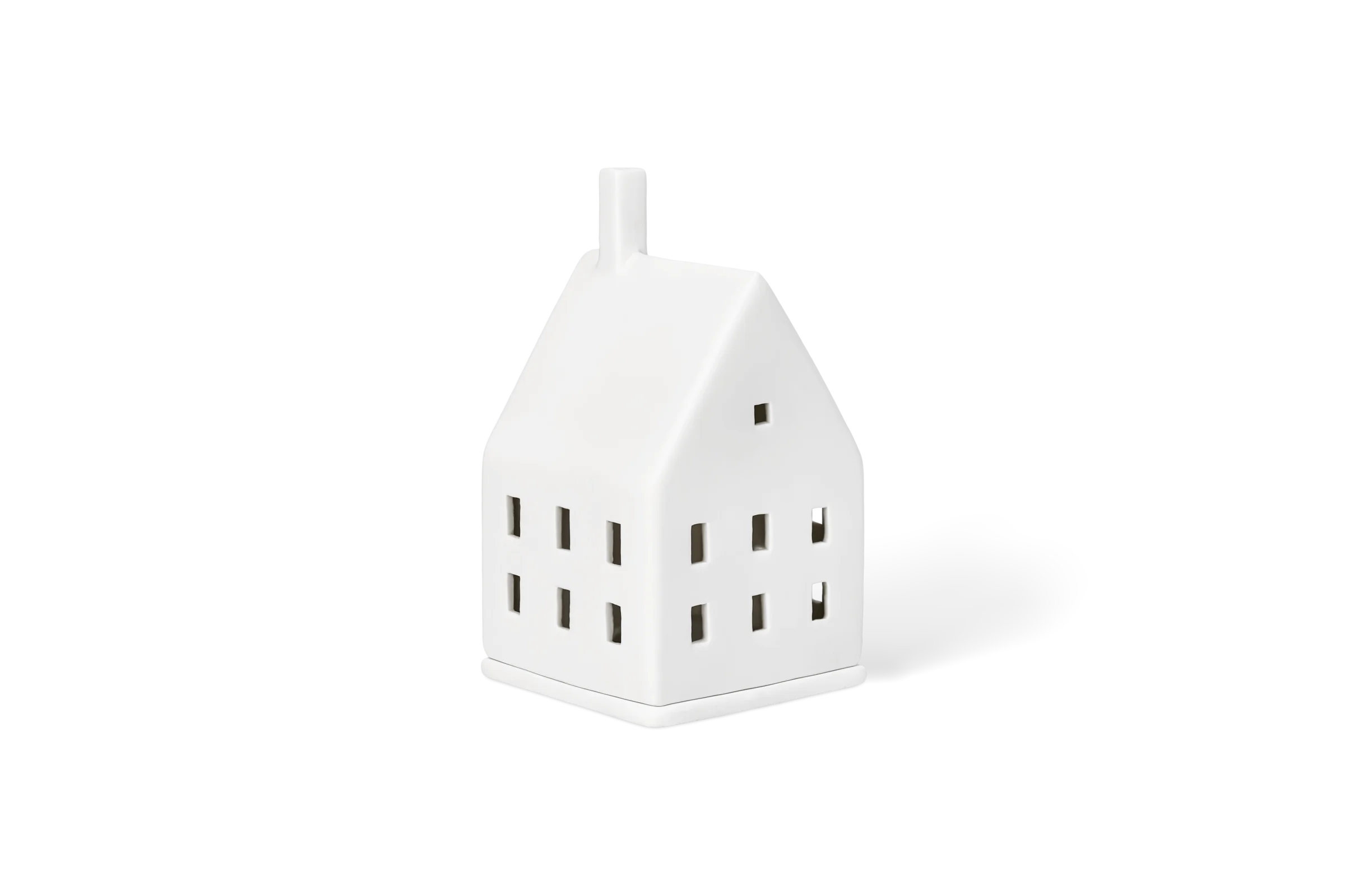 Lichthaus Lichtzauber Weißes Porzellanlichthaus mit Schornstein und ausgeschnittenen Fenstern in der vorderen Linksansicht.
